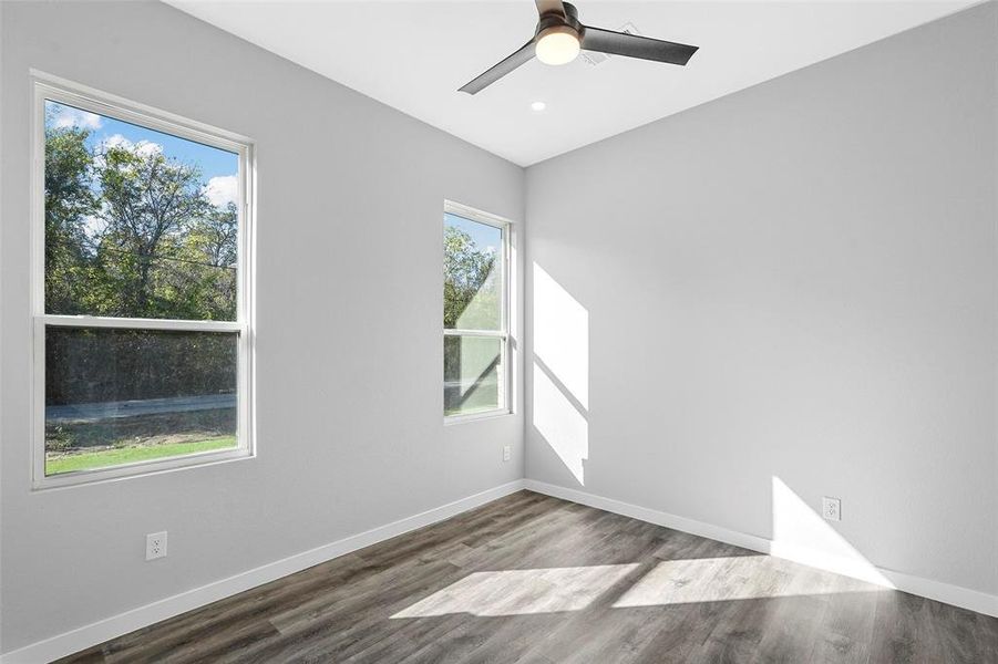 Unfurnished room featuring a wealth of natural light, wood-type flooring, and ceiling fan