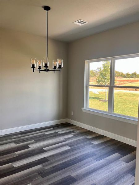 Unfurnished dining area with dark hardwood / wood-style floors and a chandelier