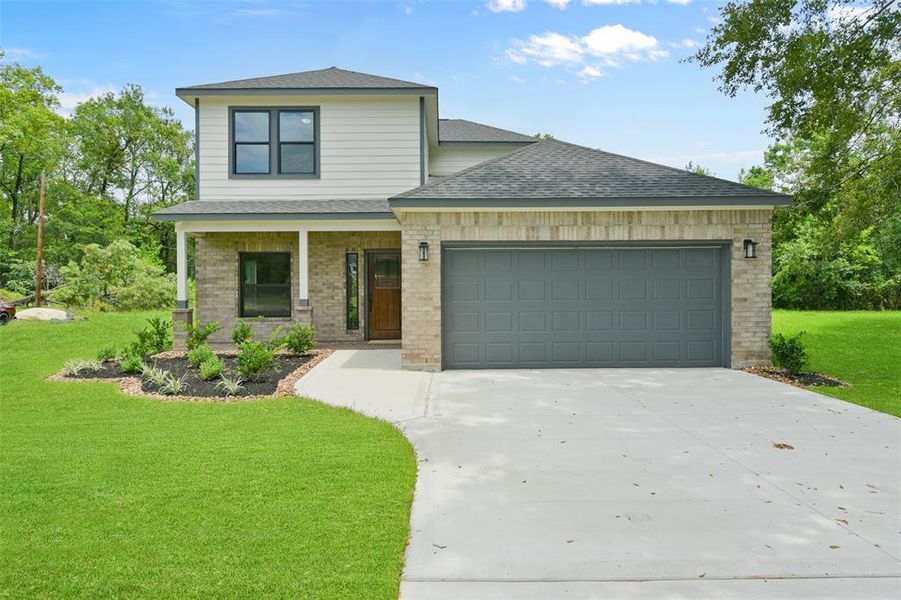 NEW CONSTRUCTION! This is a modern two-story home with a brick and siding exterior, featuring a two-car garage and a well-manicured lawn with landscaped garden beds. The property is nestled in a green, tree-rich environment.