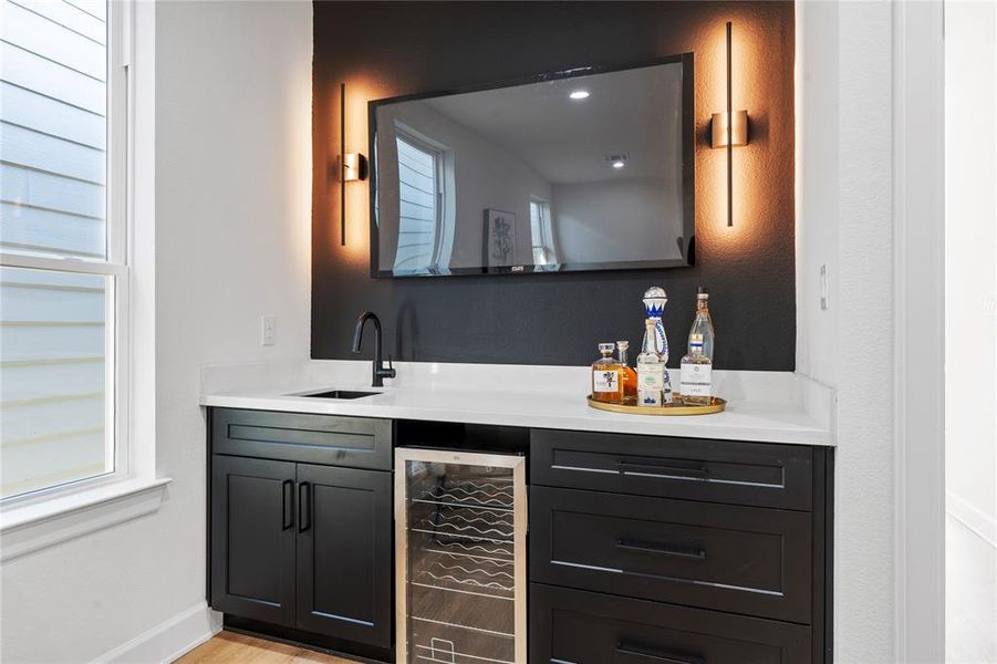 A stunning wet bar on the second floor, complete with a wine cooler, stylish black accent wall, and ample space for your TV. Perfect for entertaining guests or unwinding in style, making this a sophisticated focal point in your home.