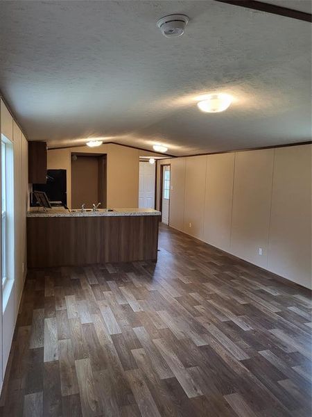 Kitchen featuring a textured ceiling, dark hardwood / wood-style floors, kitchen peninsula, sink, and light stone counters