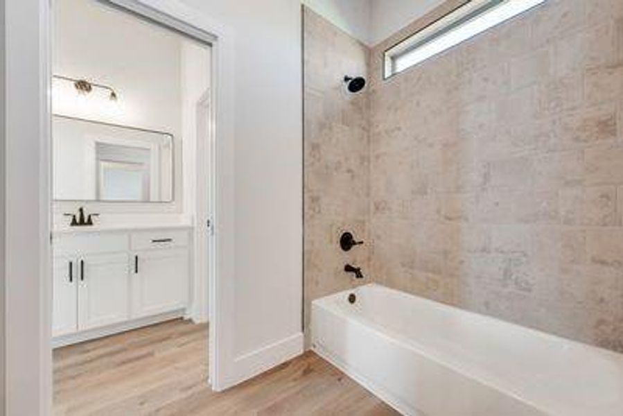 Bathroom with vanity, tiled shower / bath combo, and hardwood / wood-style flooring