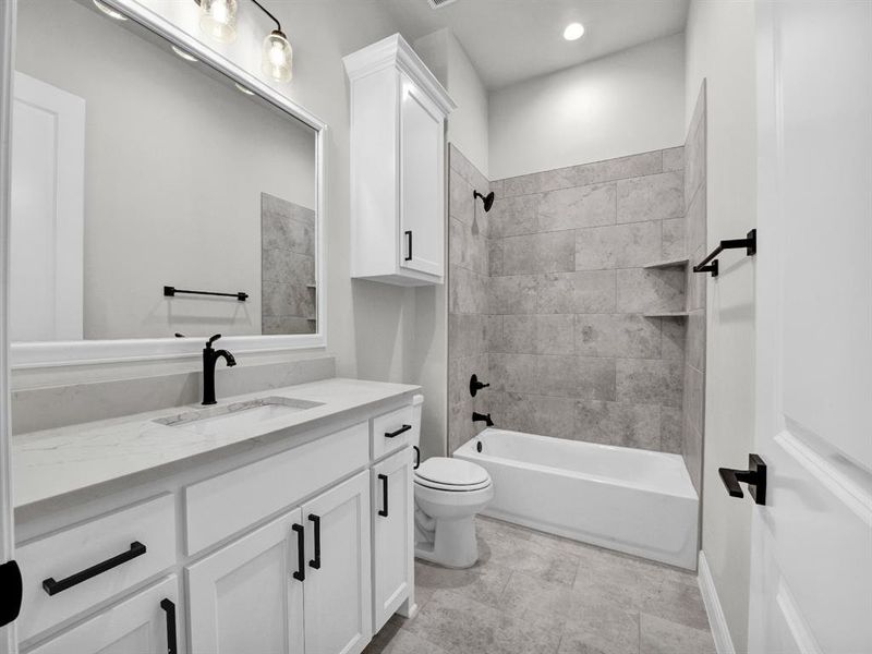 Full bathroom with tiled shower / bath, vanity, and toilet