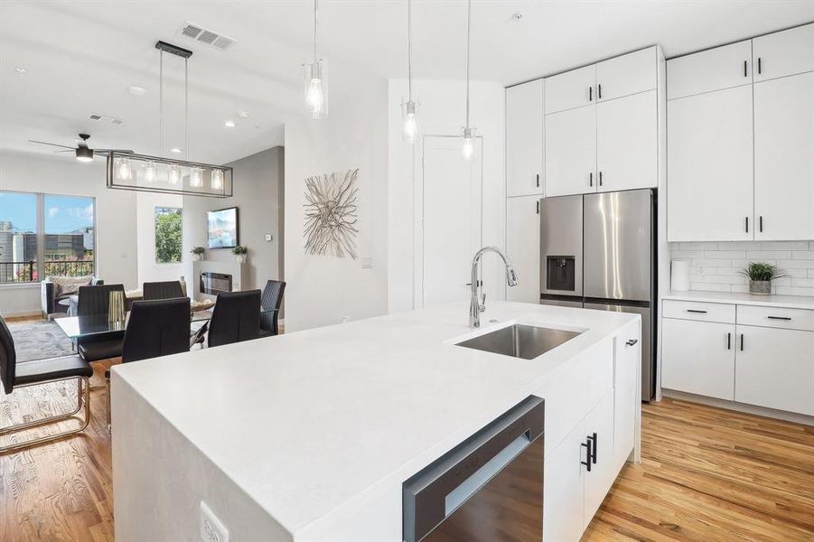 Kitchen featuring light hardwood / wood-style flooring, appliances with stainless steel finishes, sink, and an island with sink