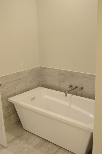 Bathroom with a free standing bathtub and tile walls