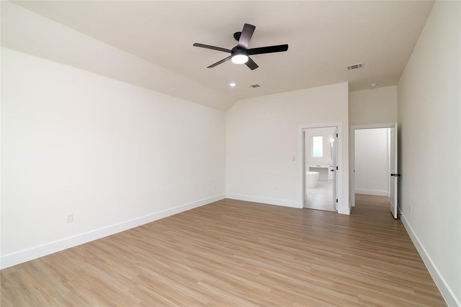 Empty room featuring ceiling fan, vaulted ceiling, and light hardwood / wood-style floors