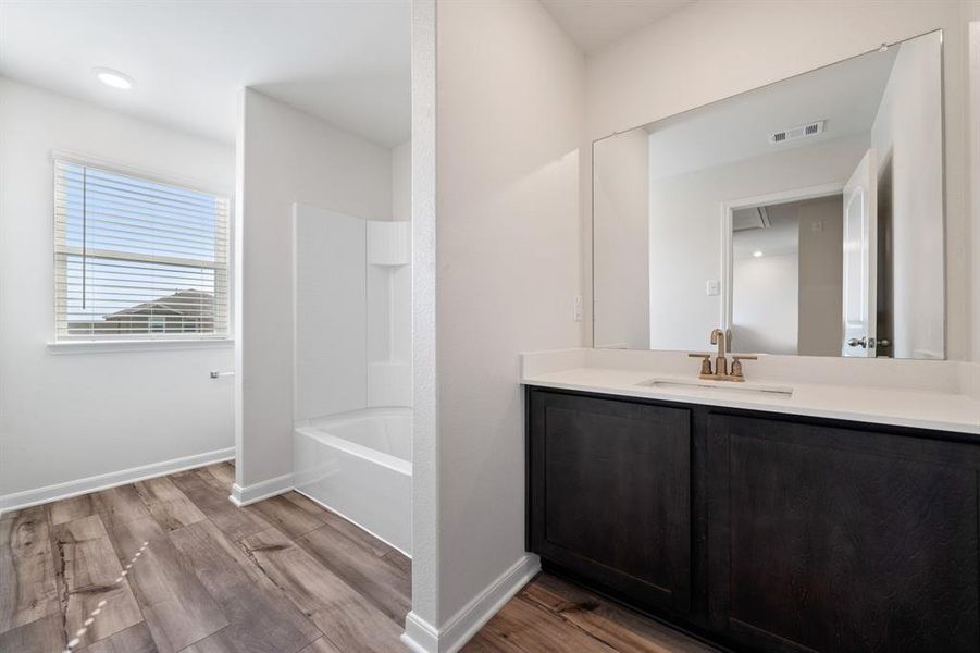 Bathroom featuring wood-type flooring, shower / bathtub combination, and vanity