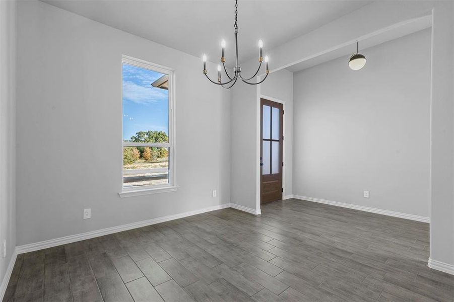 Spare room with an inviting chandelier and hardwood / wood-style floors