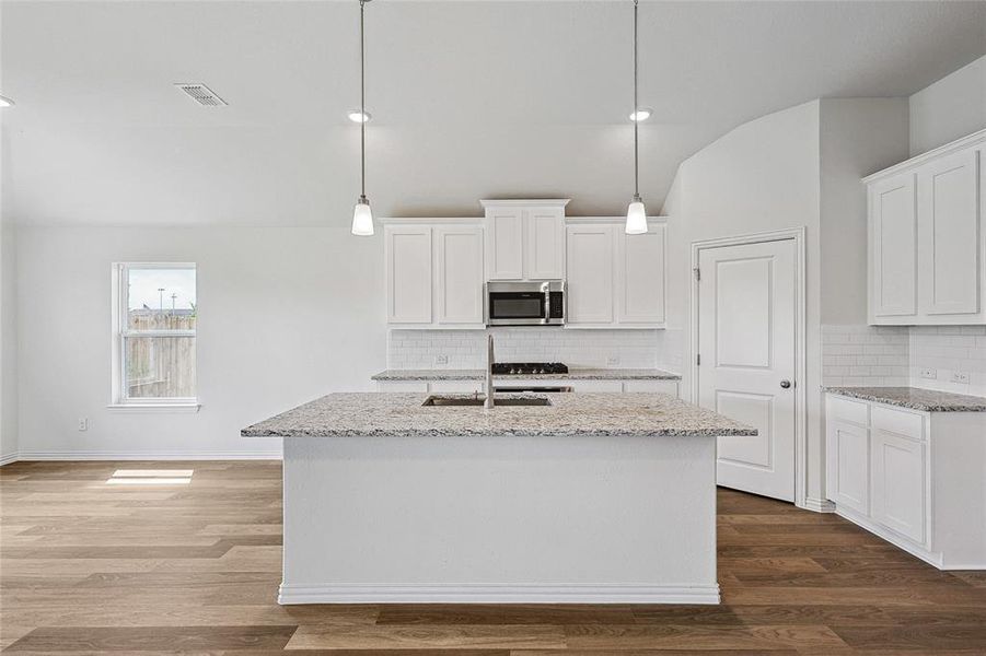 Kitchen with dark wood-type flooring, white cabinetry, backsplash, and sink