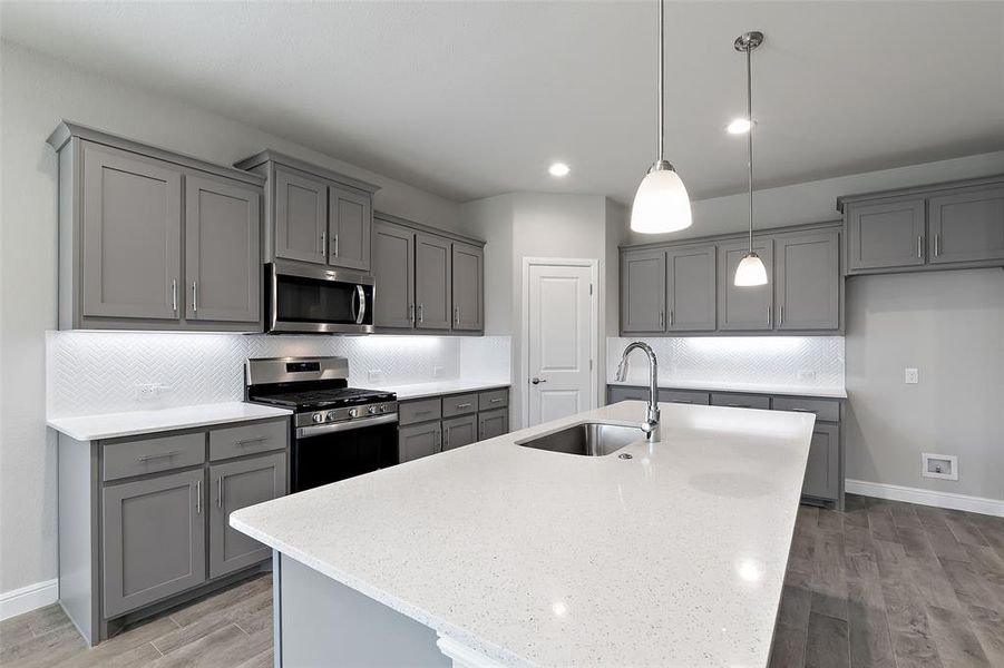 Kitchen with gray cabinetry, appliances with stainless steel finishes, and sink