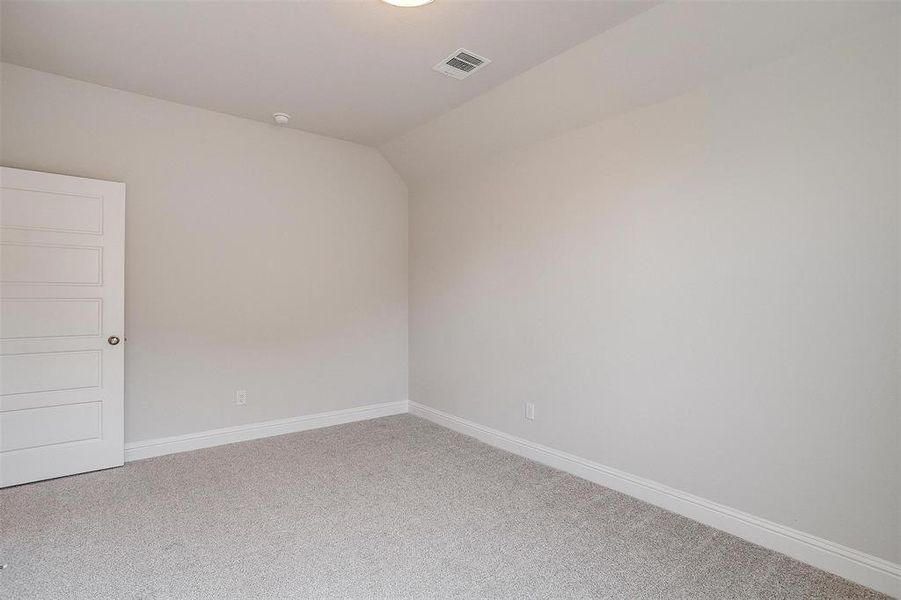 Empty room featuring lofted ceiling and carpet flooring