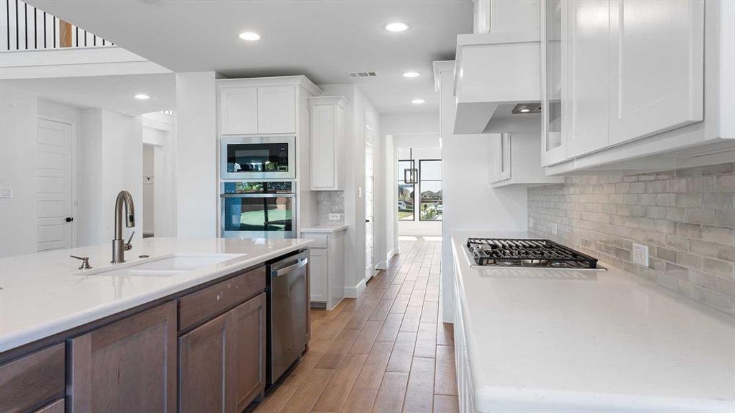 Kitchen featuring tasteful backsplash, appliances with stainless steel finishes, sink, light hardwood / wood-style floors, and white cabinets