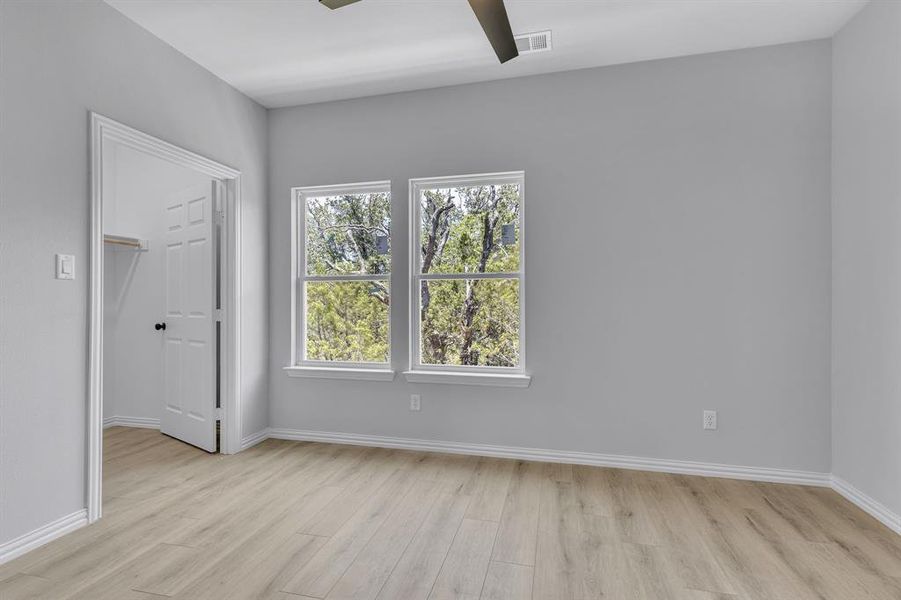 Unfurnished room featuring light hardwood / wood-style flooring, a healthy amount of sunlight, and ceiling fan