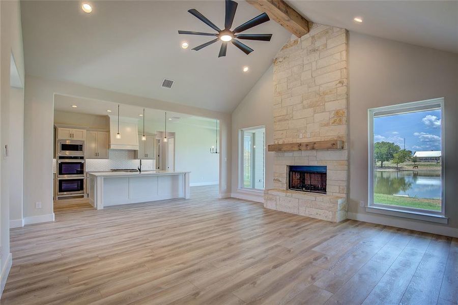 Unfurnished living room featuring high vaulted ceiling, a healthy amount of sunlight, light hardwood / wood-style flooring, and beamed ceiling