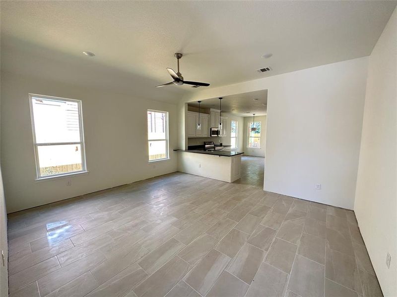 Unfurnished living room featuring ceiling fan and plenty of natural light