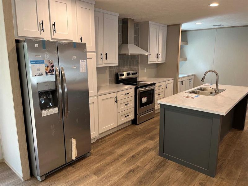 Kitchen featuring a kitchen island with sink, wood-type flooring, wnergy star stainless steel appliances