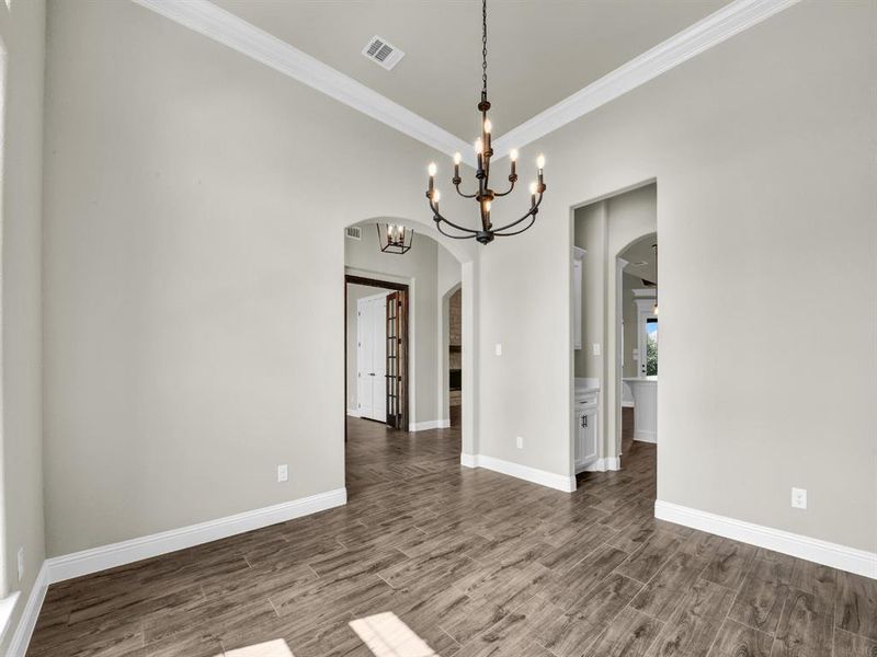 Unfurnished dining area featuring crown molding, dark hardwood / wood-style flooring, and a notable chandelier