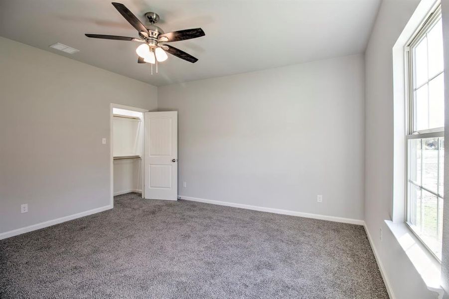 Unfurnished bedroom featuring ceiling fan, carpet flooring, a closet, and a walk in closet