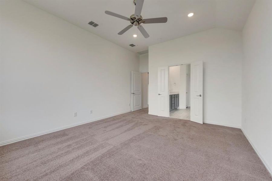 Carpeted empty room featuring ceiling fan and lofted ceiling