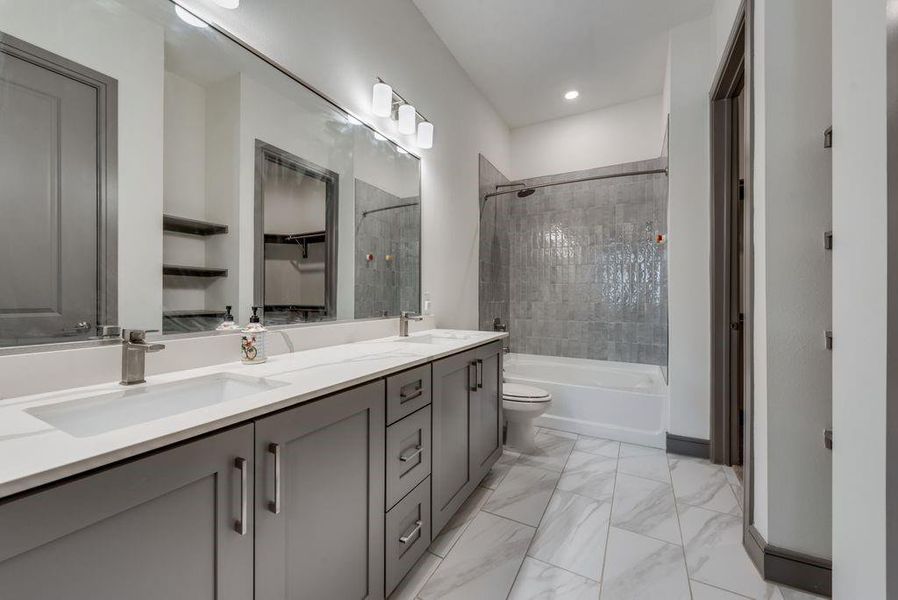 Full bathroom with tile flooring, tiled shower / bath, oversized vanity, toilet, and dual sinks