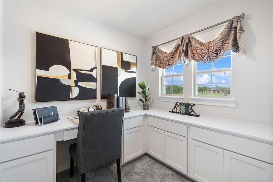 Carpeted office space featuring built in desk