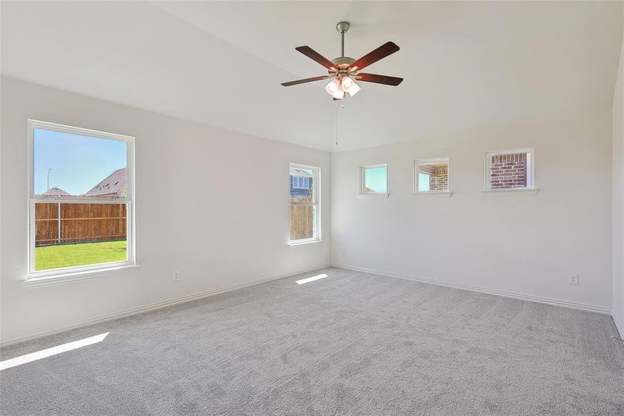 Empty room with ceiling fan, light carpet, and vaulted ceiling