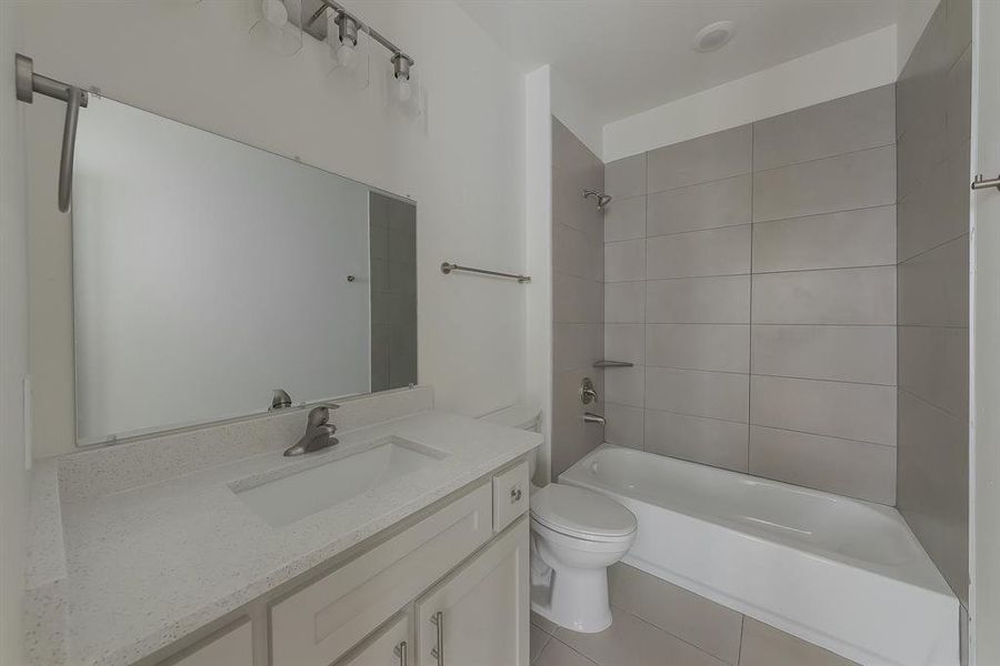 Full bathroom with tile patterned flooring, vanity, toilet, and tiled shower / bath