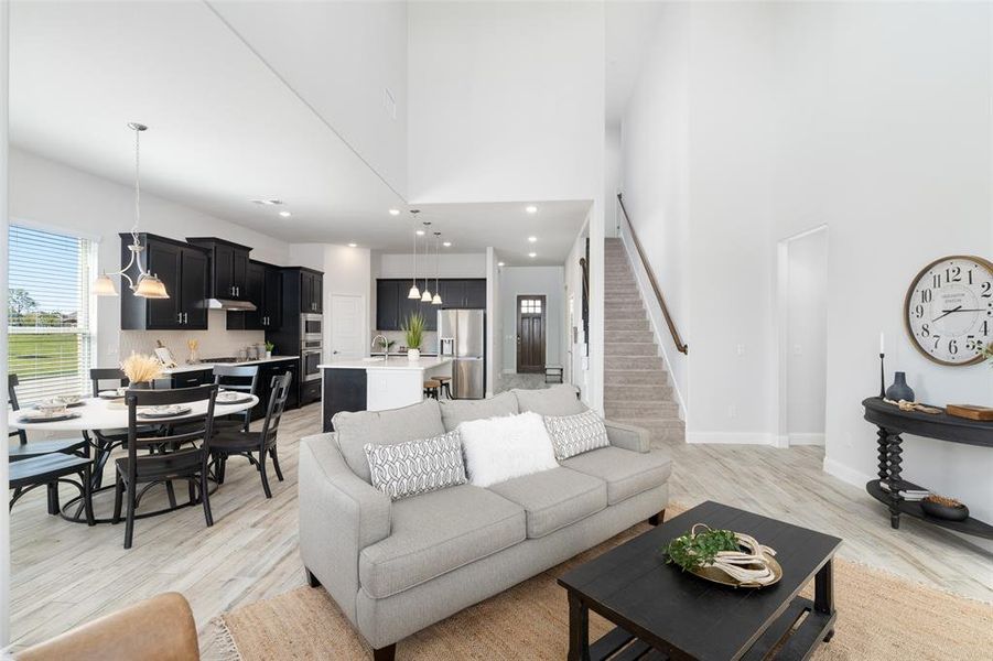 Living room featuring light hardwood / wood-style flooring, a high ceiling, an inviting chandelier, and sink