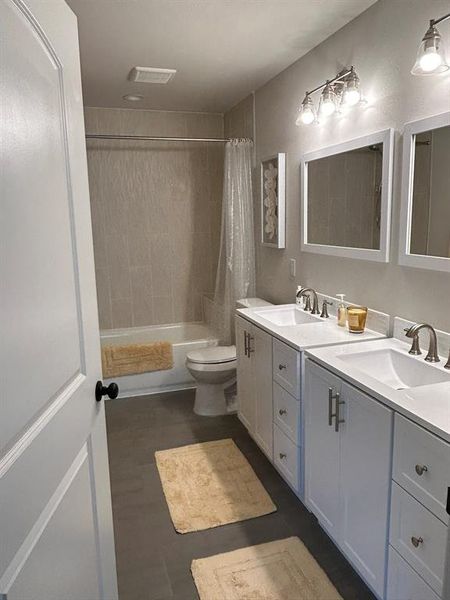 Full bathroom with shower / tub combo, dual vanity, and toilet