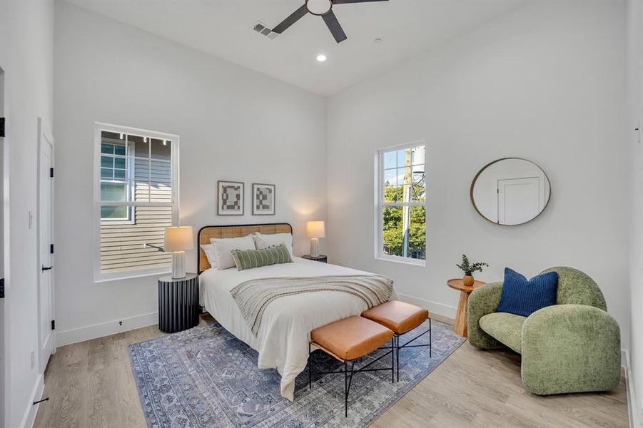 Bedroom featuring a towering ceiling, light hardwood / wood-style floors, and ceiling fan