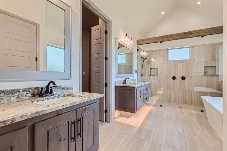 Bathroom with tile patterned flooring, double vanity, vaulted ceiling, and independent shower and bath