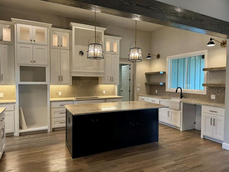 Kitchen with decorative light fixtures, a center island, beamed ceiling, and white cabinets