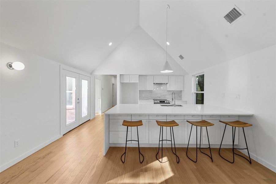 Kitchen with light wood-type flooring, plenty of natural light, sink, and white cabinetry