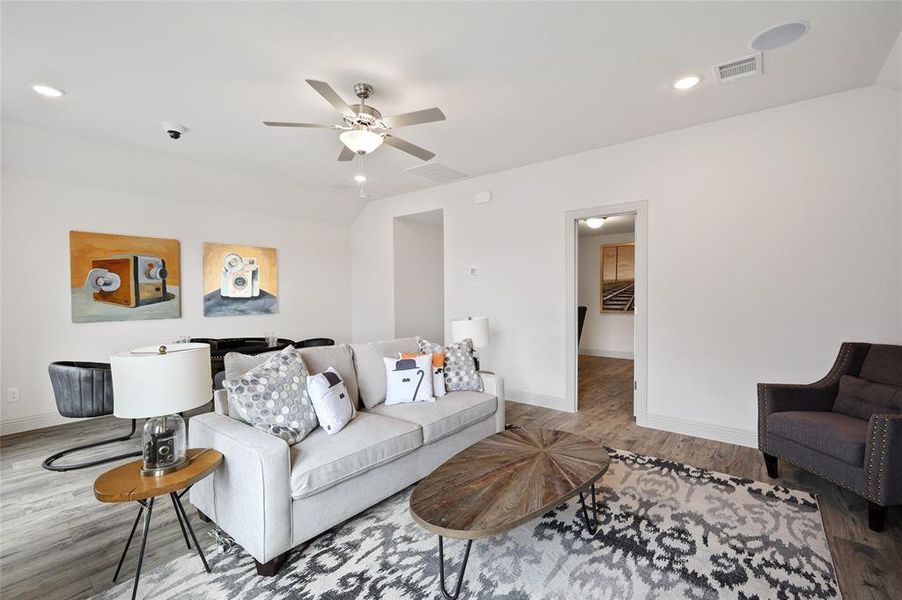 Living room with lofted ceiling, ceiling fan, and light hardwood / wood-style floors