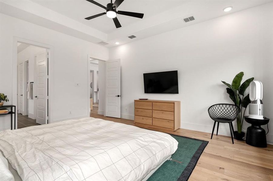 Spacious primary bedroom with ceiling fan and light hardwood / wood-style flooring
