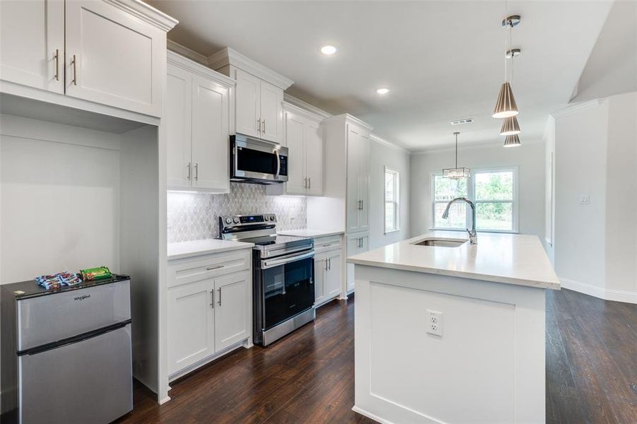 Kitchen featuring dark wood-type flooring, white cabinets, sink, and stainless steel appliances