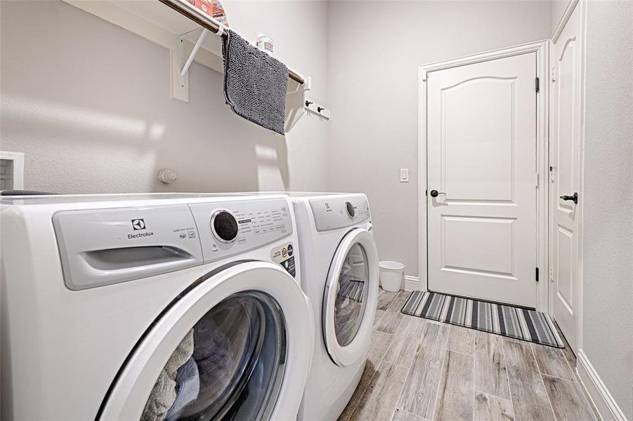 Washroom with light hardwood / wood-style floors and washing machine and dryer