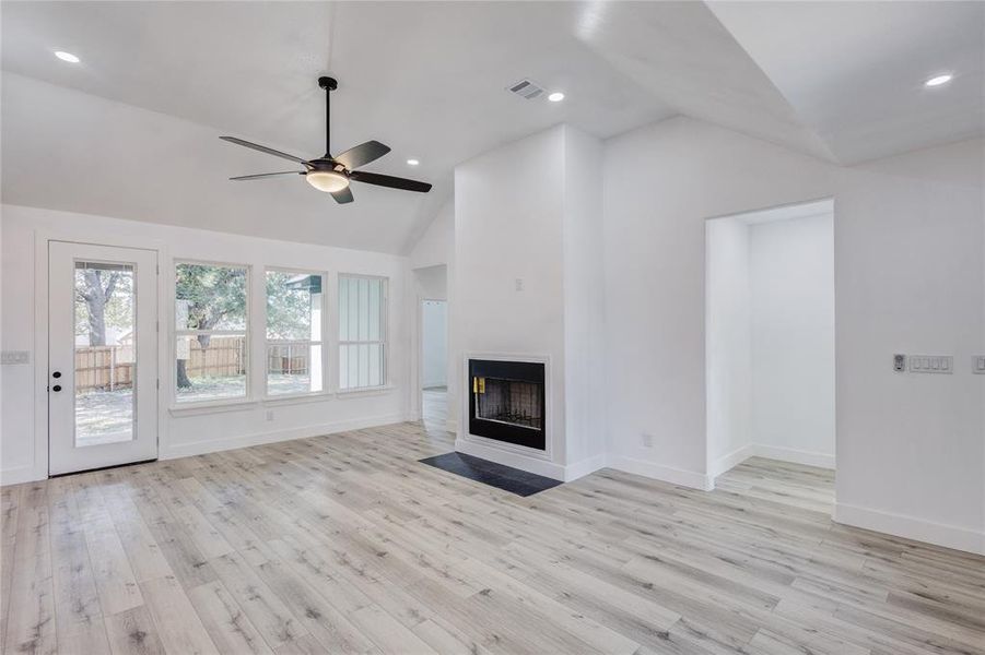 Unfurnished living room featuring lofted ceiling, ceiling fan, and light hardwood / wood-style flooring