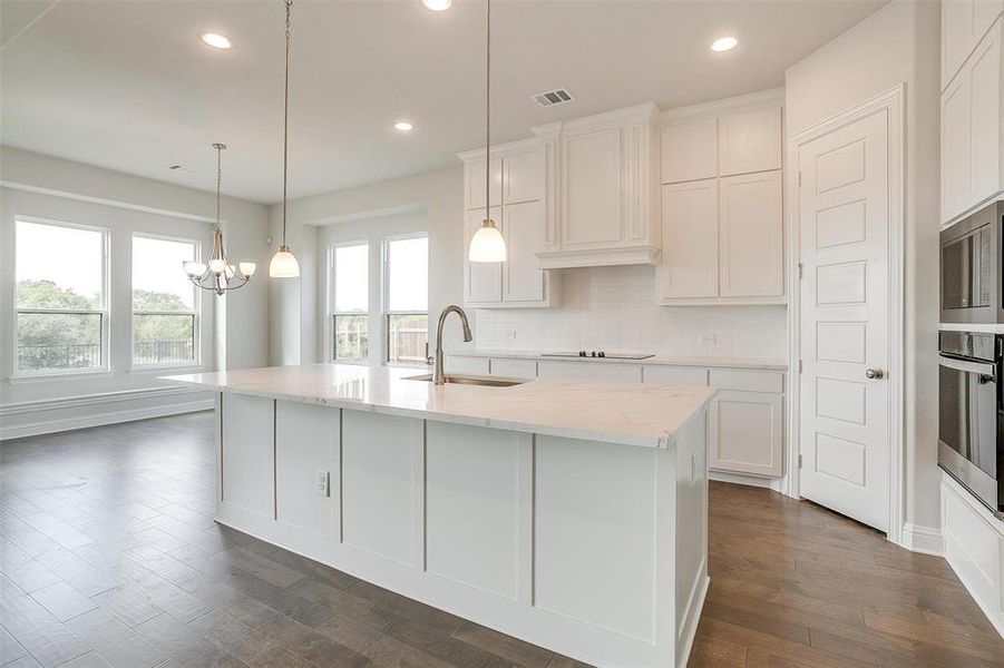 Kitchen featuring sink, appliances with stainless steel finishes, a kitchen island with sink, and white cabinetry