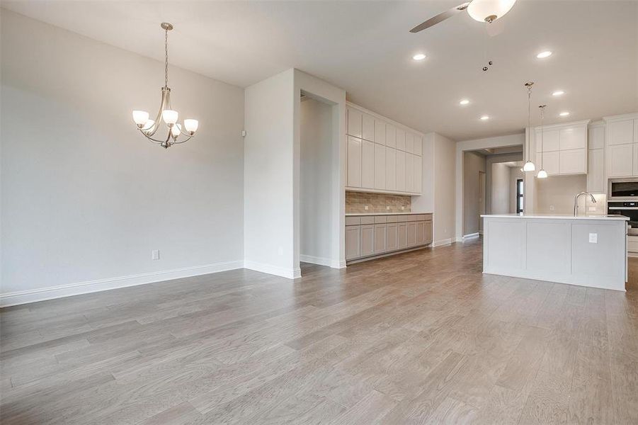 Unfurnished living room with ceiling fan with notable chandelier, light hardwood / wood-style flooring, and sink