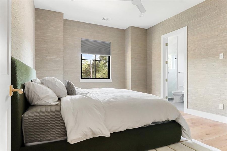 Bedroom with ensuite bath, ceiling fan, and hardwood / wood-style flooring