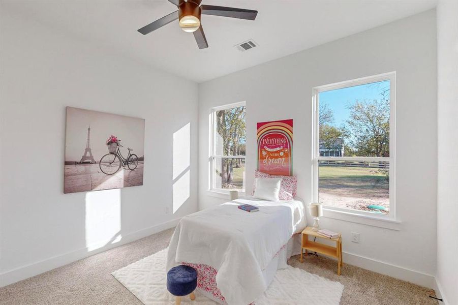 Bedroom featuring carpet, multiple windows, and ceiling fan