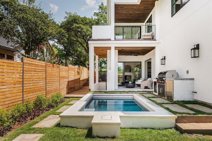 European inspired backyard is complete with in-ground pool and summer kitchen that features a Wolf Outdoor Grill.