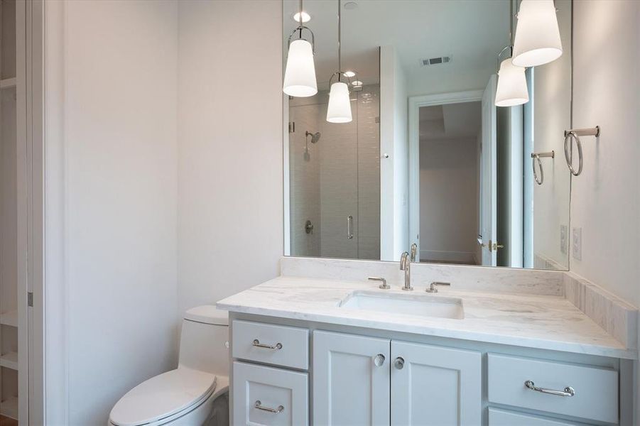 Bathroom with vanity, toilet, and a shower with shower door