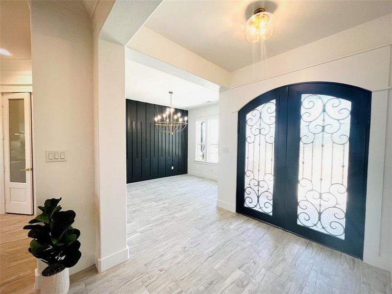 Foyer entrance with light hardwood / wood-style floors, a notable chandelier, and french doors