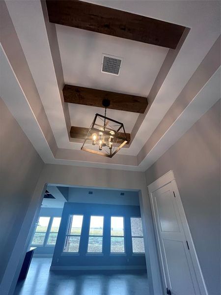 Details with a raised ceiling, beamed ceiling, and a chandelier