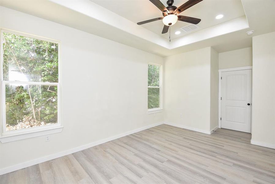 Primary Bedroom with Tray Ceiling, LED Lighting, and Ceiling Fan.