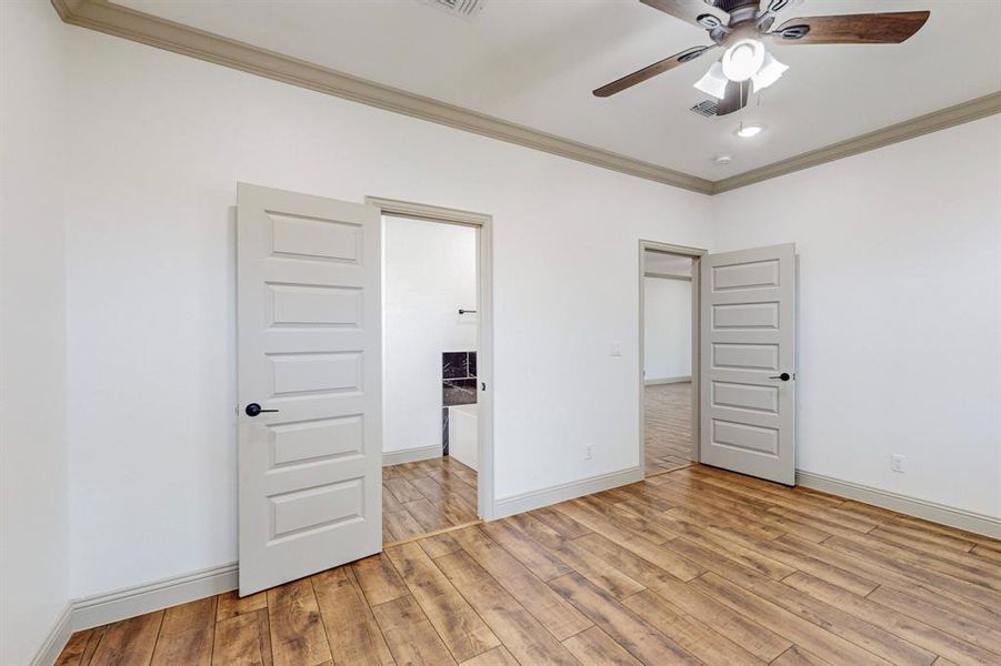 Unfurnished bedroom with crown molding, ceiling fan, and light hardwood / wood-style floors