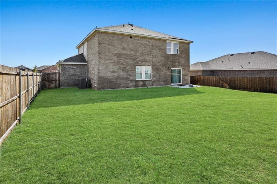 Rear view of house with a lawn and central AC