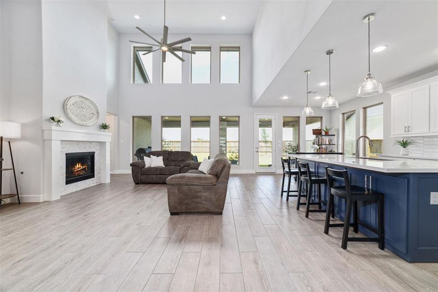 This is a bright, modern open floor-plan living space featuring high 21 foot ceilings with a cozy fireplace, and direct access to an outdoor patio.